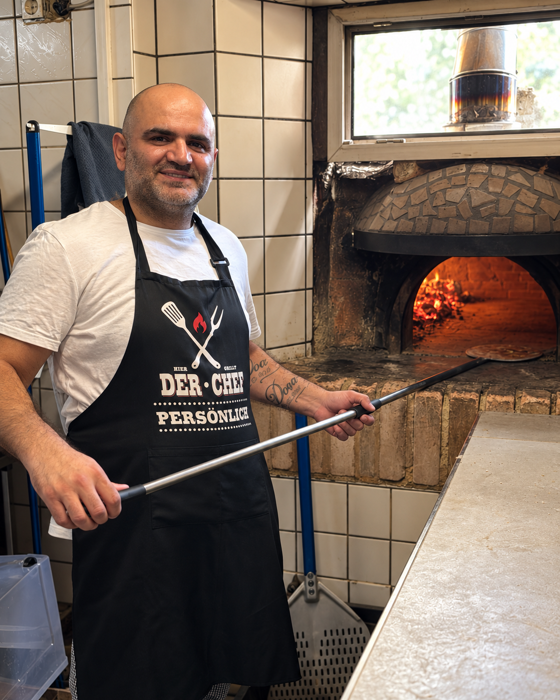 Pizzabäcker mit Pizzaschieber am brennenden Holzofen im Vulcano